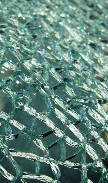 Nahaufnahme von kunstvoll gemustertem Glas, das schimmernde, durchscheinende Formen zeigt, die an ein feines Netz erinnern.